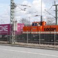 Orange Lokomotive zieht Container-Güterzug (Symbol Bahn-Handelskorridor / neue Seidenstraße)