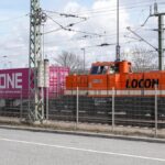 Orange Lokomotive zieht Container-Güterzug (Symbol Bahn-Handelskorridor / neue Seidenstraße)