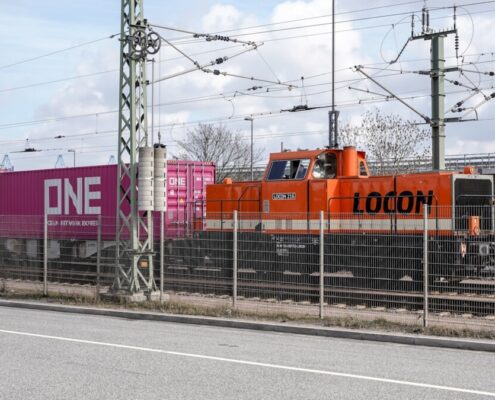 Orange Lokomotive zieht Container-Güterzug (Symbol Bahn-Handelskorridor / neue Seidenstraße)