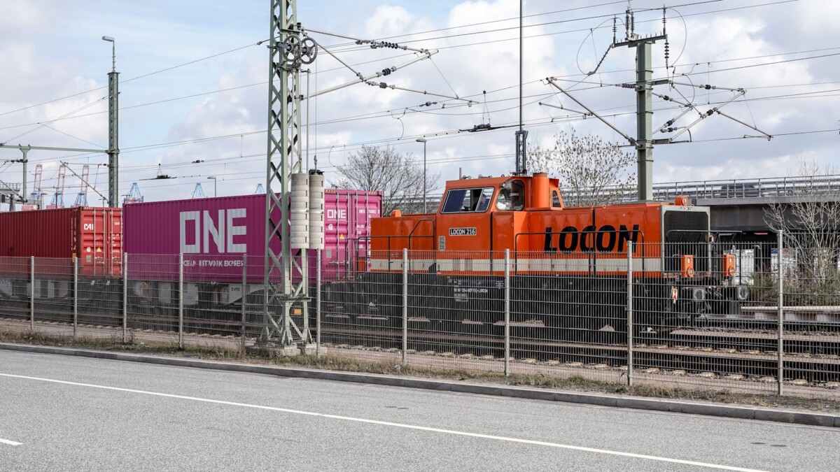 Orange Lokomotive zieht Container-Güterzug (Symbol Bahn-Handelskorridor / neue Seidenstraße)