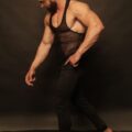 Muskulöser Mann im Tank-Top, dunkler Studiohintergrund