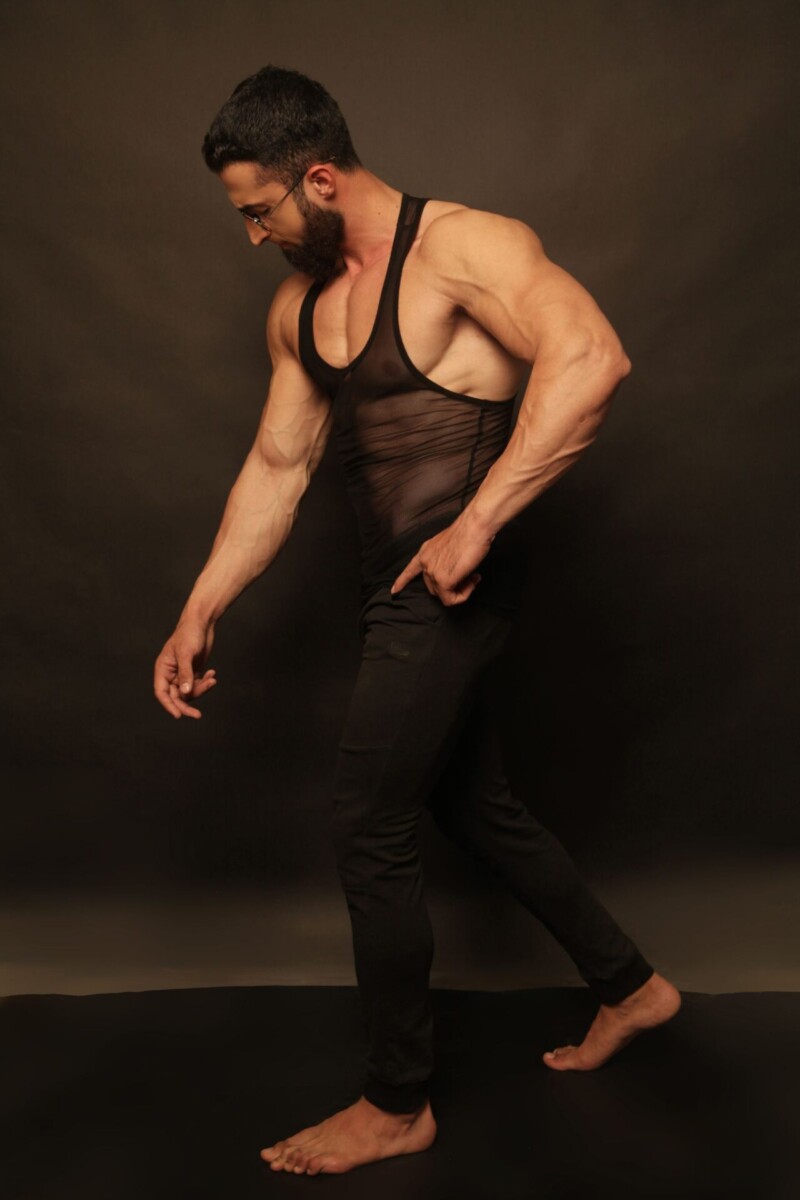 Muskulöser Mann im Tank-Top, dunkler Studiohintergrund