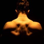 Rückenansicht eines muskulösen Mannes im Schatten
