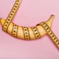 Banane mit pinkem Maßband umwickelt, pinker Hintergrund