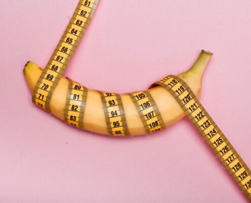 Banane mit pinkem Maßband umwickelt, pinker Hintergrund