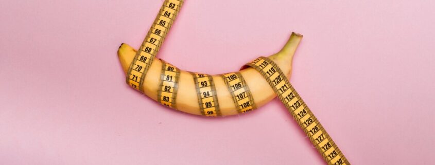 Banane mit pinkem Maßband umwickelt, pinker Hintergrund