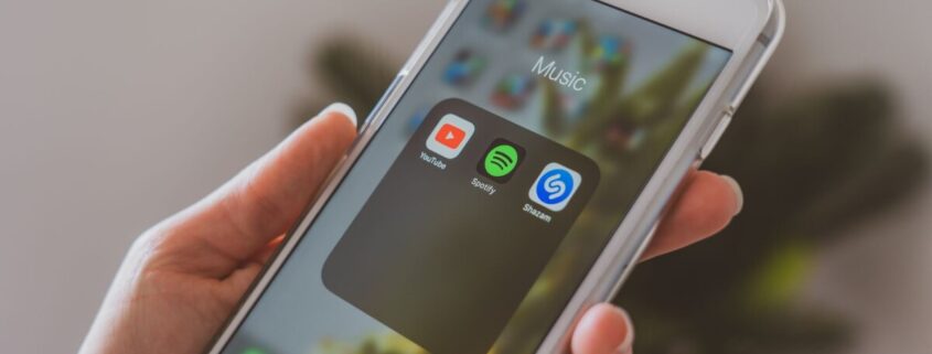 Hand hält Smartphone mit Musik-Apps wie Shazam und Spotify
