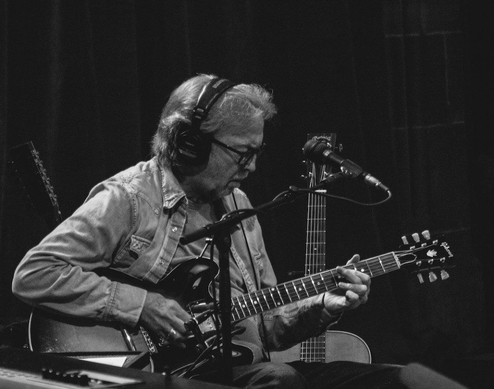 Eric Clapton mir E-Gitarre und Kopfhoerern