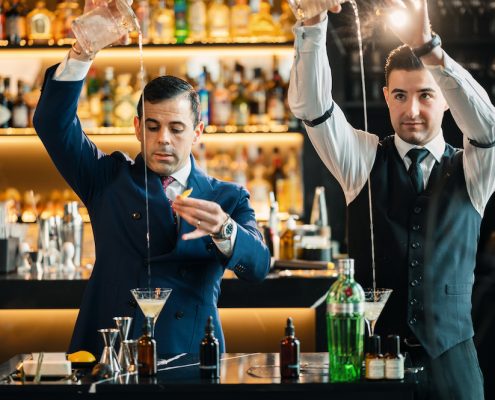 Zwei Barkeeper mixen nebeneinander einen Martini