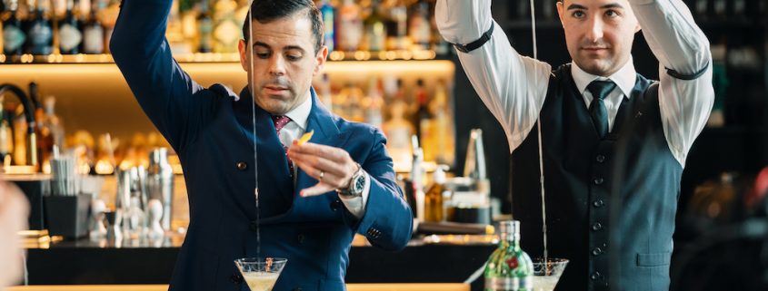 Zwei Barkeeper mixen nebeneinander einen Martini