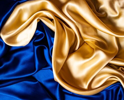 Nahaufnahme blau-goldener Seidenstoff, edel drapiert