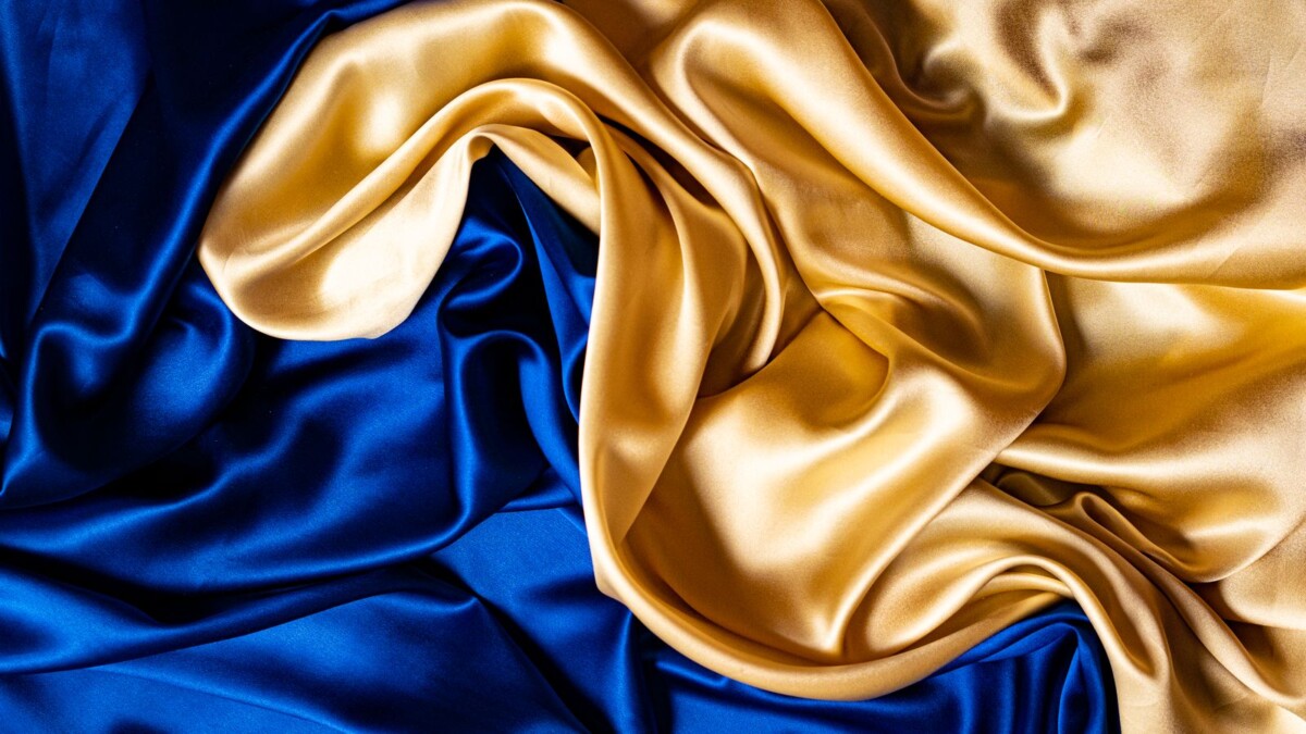 Nahaufnahme blau-goldener Seidenstoff, edel drapiert