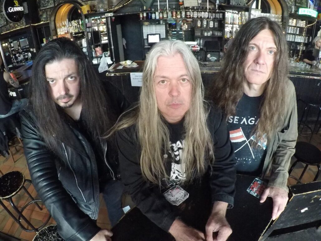 Frank Blackfire & Band, drei Musiker mit langen Haaren an einer Bartheke