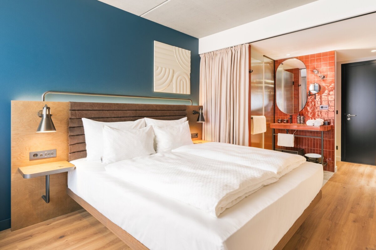 Smart-Zimmer mit petrolfarbener Wand und rot gefliestem Bad im Hotel Schani Naschmarkt