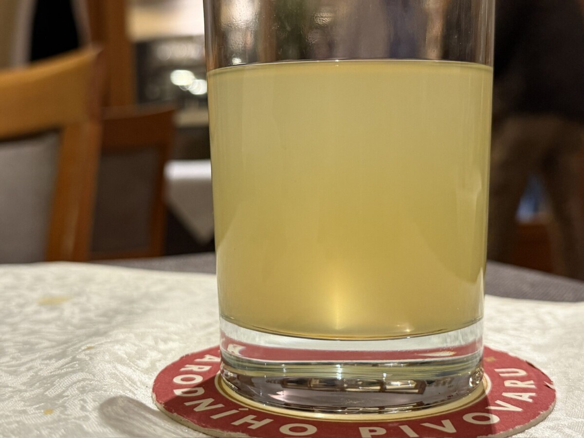 Glas mit gelblicher Flüssigkeit auf einem Bierdeckel in einer Gaststätte