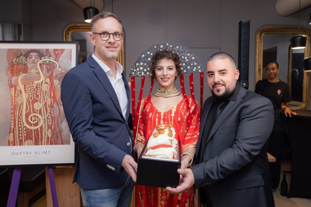 Die beiden Eiswerkstatt-Gründer mit Hygieia-Muse Enya Rock vor dem Klimt-Bild