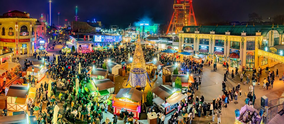 Wintermarkt am Riesenradplatz im Prater: Standlldorf mit Christbaum, Menschen und Riesenrad-Kulisse bei Nacht