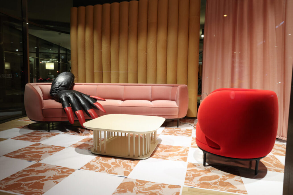 Rosafarbenes Wittmann Sofa und roter Fauteuil vor gefälteltem Vorhang im Showroom